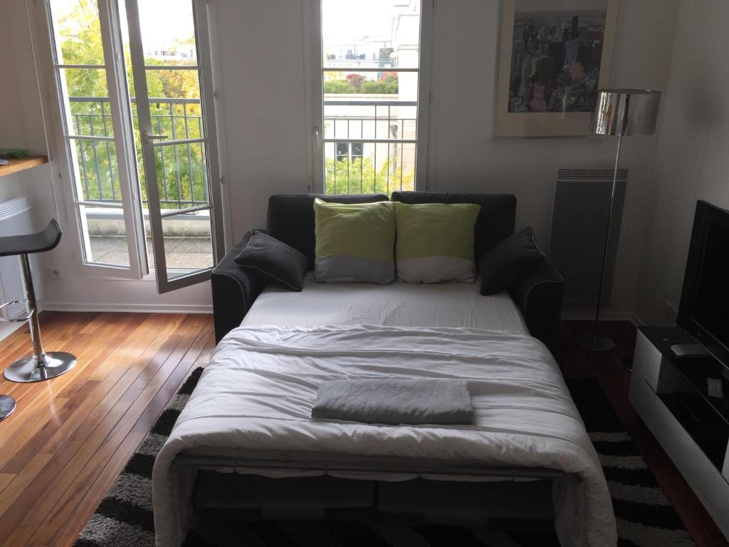 a bed in a living room with two windows at Appartement near Disneyland in Serris