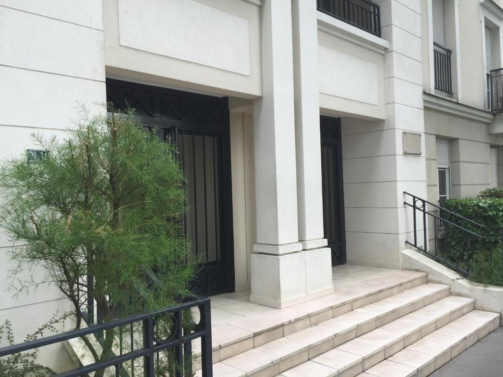 a white building with stairs in front of a door at Appartement near Disneyland in Serris