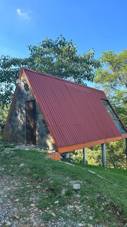 a small house with a red roof on a field at Cabañas Metztonalli in Xilitla