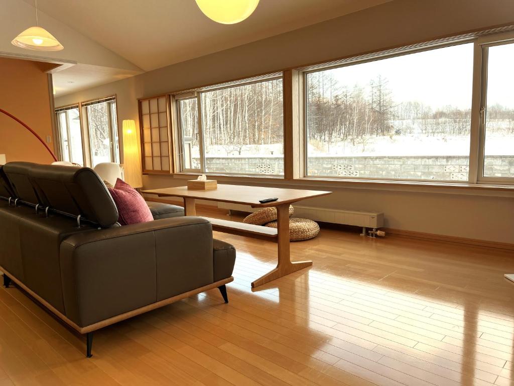 a living room with a couch and a table and windows at Villa和心 in Asahikawa