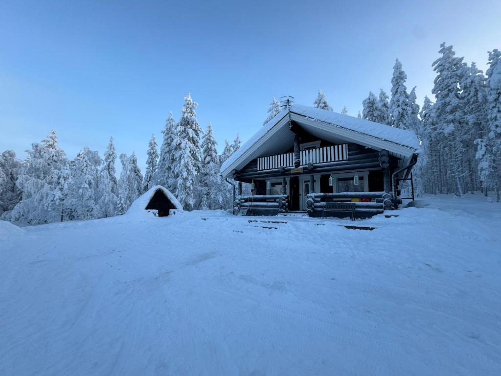 Eine Blockhütte im Schnee, im Hintergrund Bäume. in der Unterkunft Vaaranpää in Kotaniemi