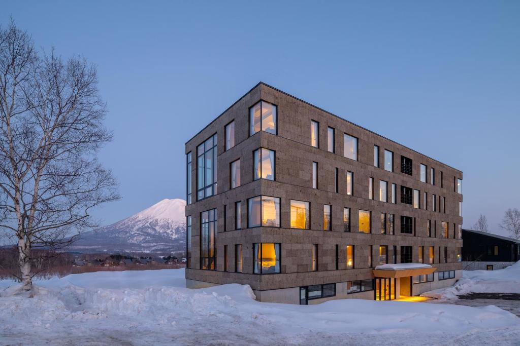 a building in the snow with a mountain in the background at The 1898 Niseko in Kutchan