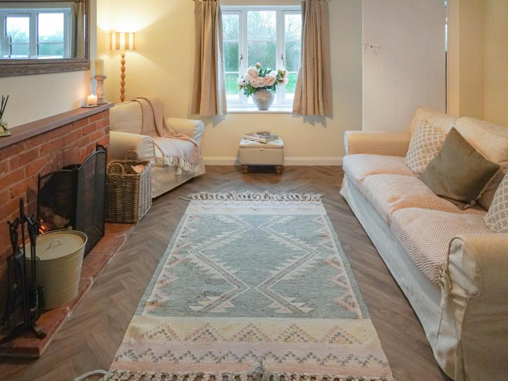 a living room with a couch and a fireplace at Corbetts Lodge Cottage in Swaffham