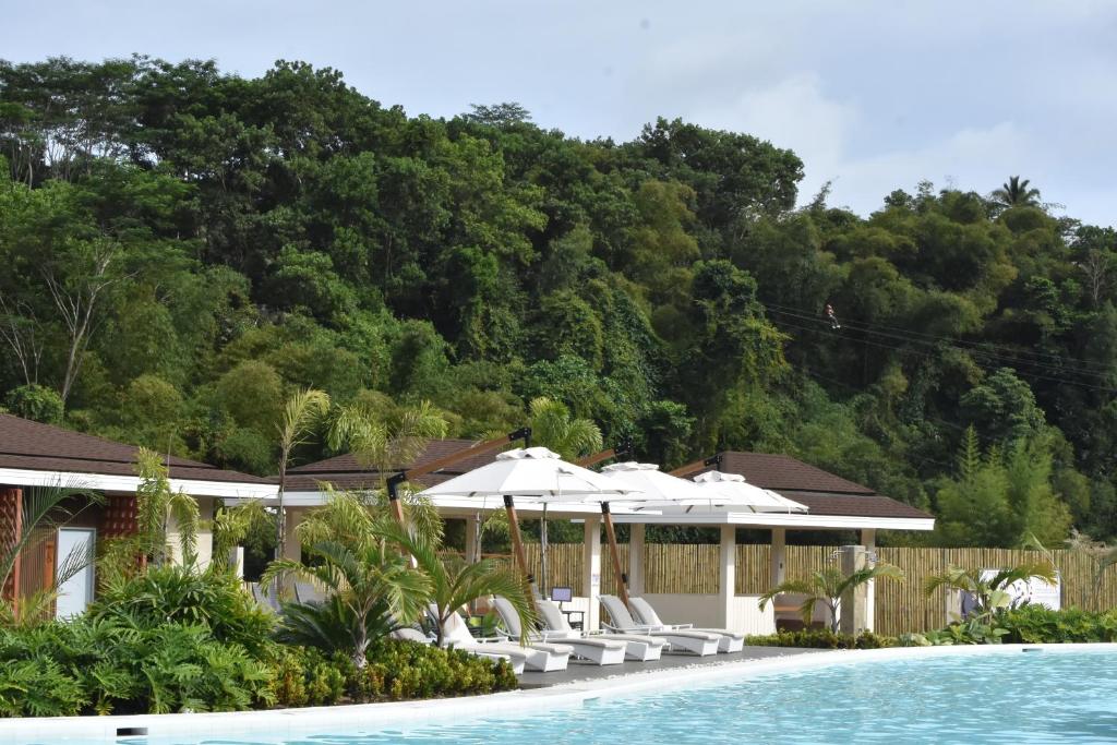 a pool with white umbrellas and chairs next to a resort at Kenjelo Farm and Recreation Resort in Dullan