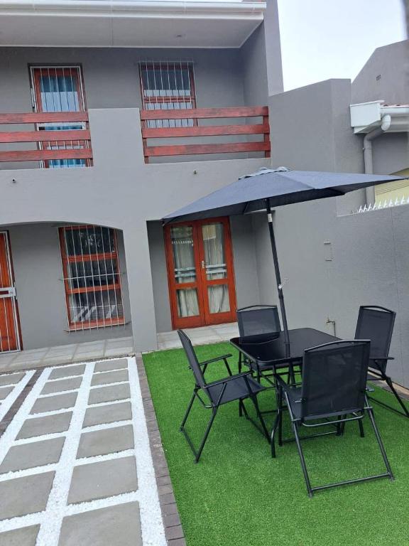 a patio with a table and chairs and an umbrella at Capetown Adilo Villa 2 in Cape Town