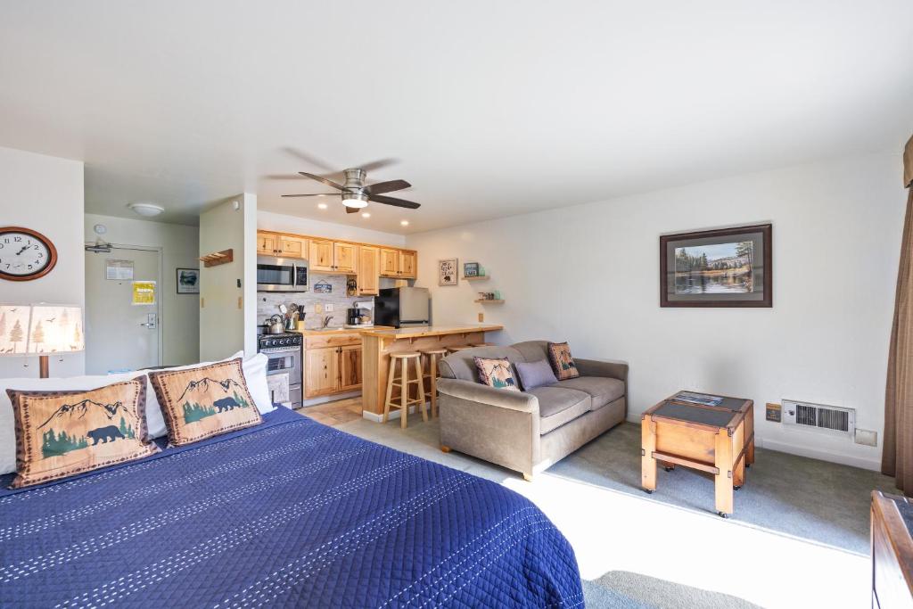 a bedroom with a bed and a couch and a kitchen at Cozy Studio w/ Partial Lake view #223 at Donner Lake Village in Truckee