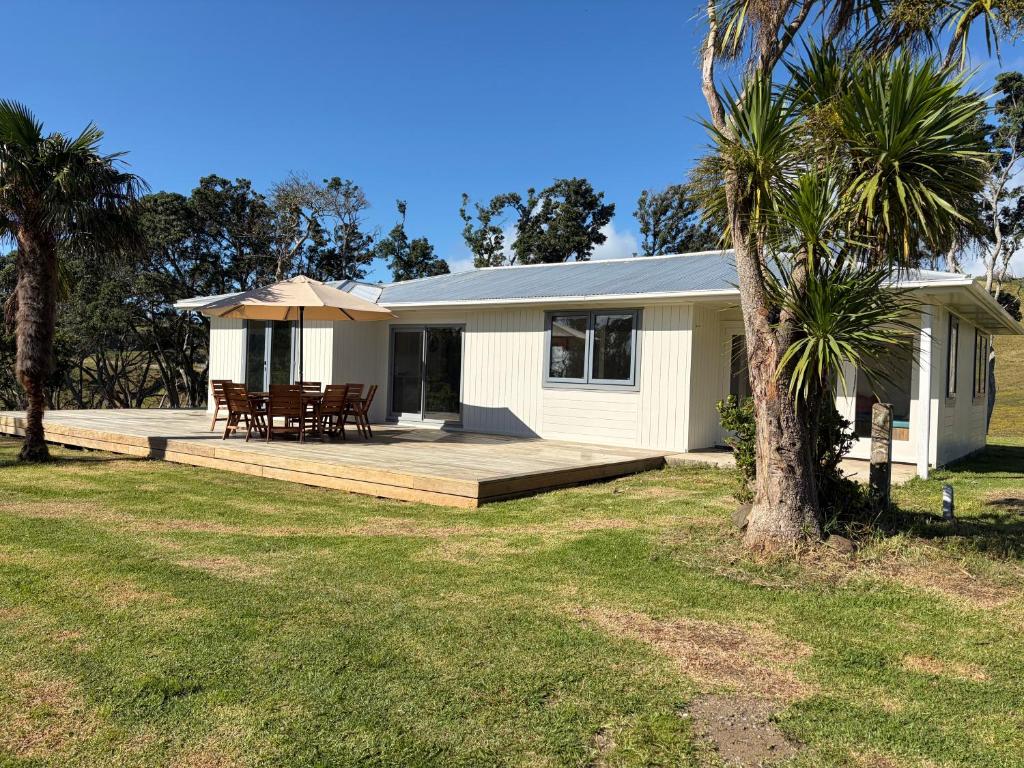 a house with a deck and a table and chairs at Pouto Farms Packhouse - Coastal Farmhouse in Pouto