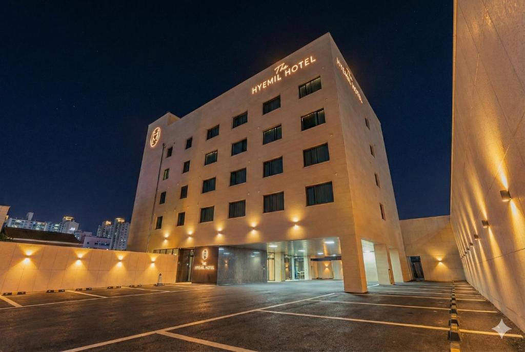 a hotel building with a parking lot at night at 구미 더혜밀호텔 in Gumi