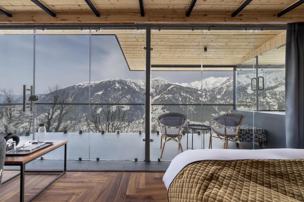 a bedroom with a view of the mountains through windows at Echor Himalayan Sky Cabins Sethan, Manali in Manāli