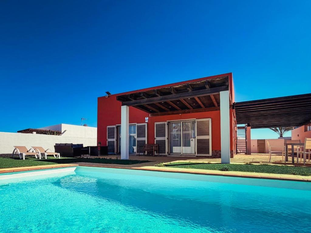 a house with a swimming pool in front of a house at Villa Solara in Caleta De Fuste