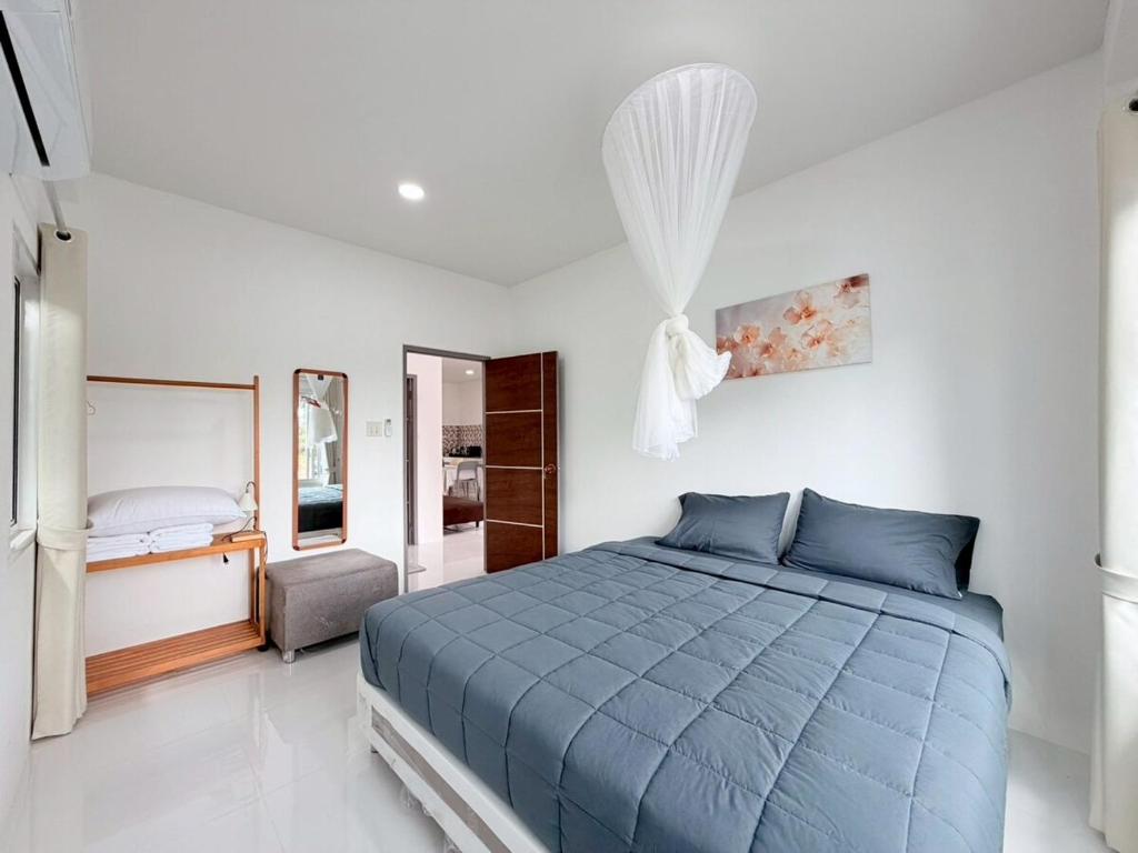 a bedroom with a blue bed in a white room at Ban Belife14 in Ban Tha Chin (1)