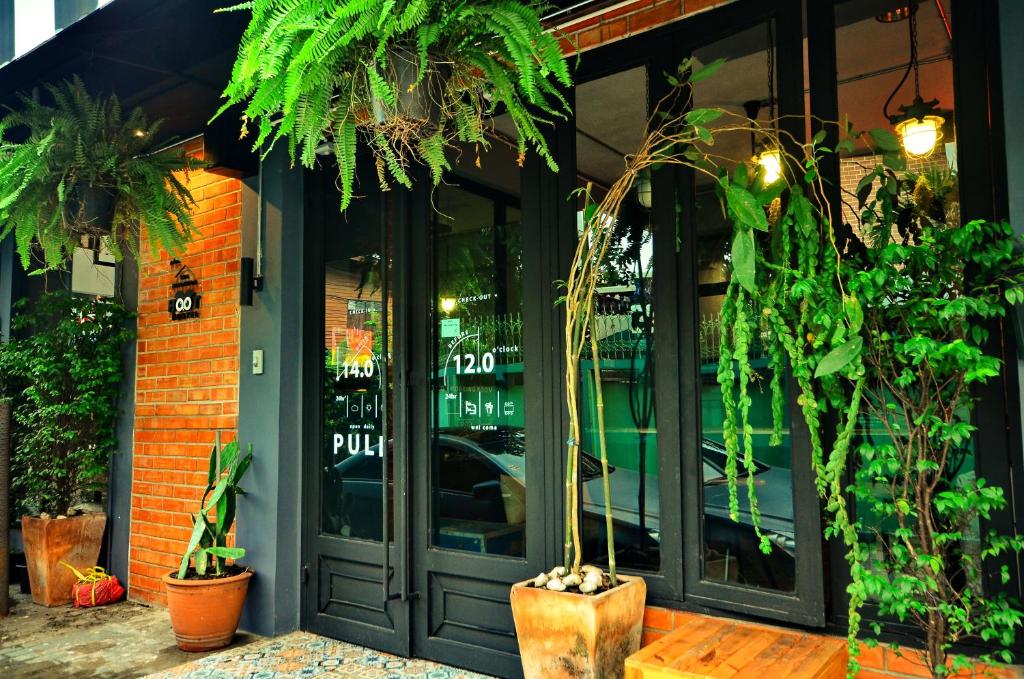 a store front with glass doors and potted plants at HOOT Hostel & Ratchada in Bangkok