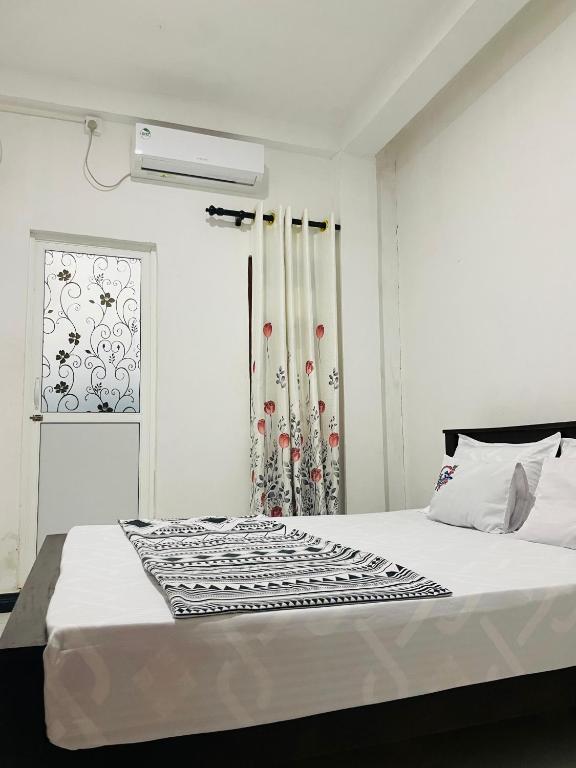 a white bedroom with a bed and a window at Kumara Guest House Dambulla in Dambulla