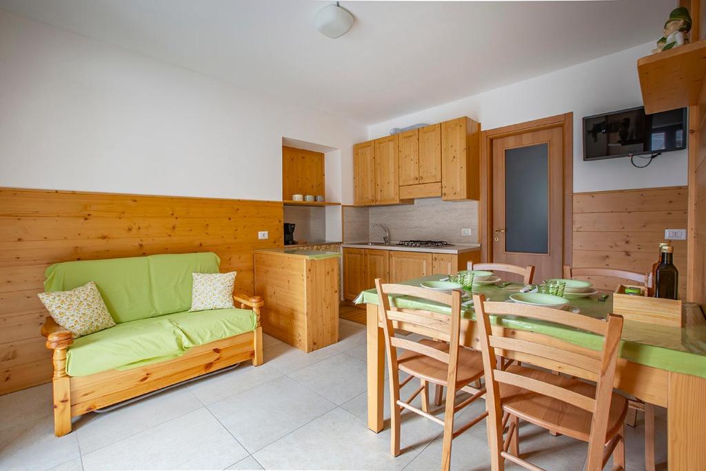 a kitchen and dining room with a green couch and a table at Il Nido di Somadino in Casargo