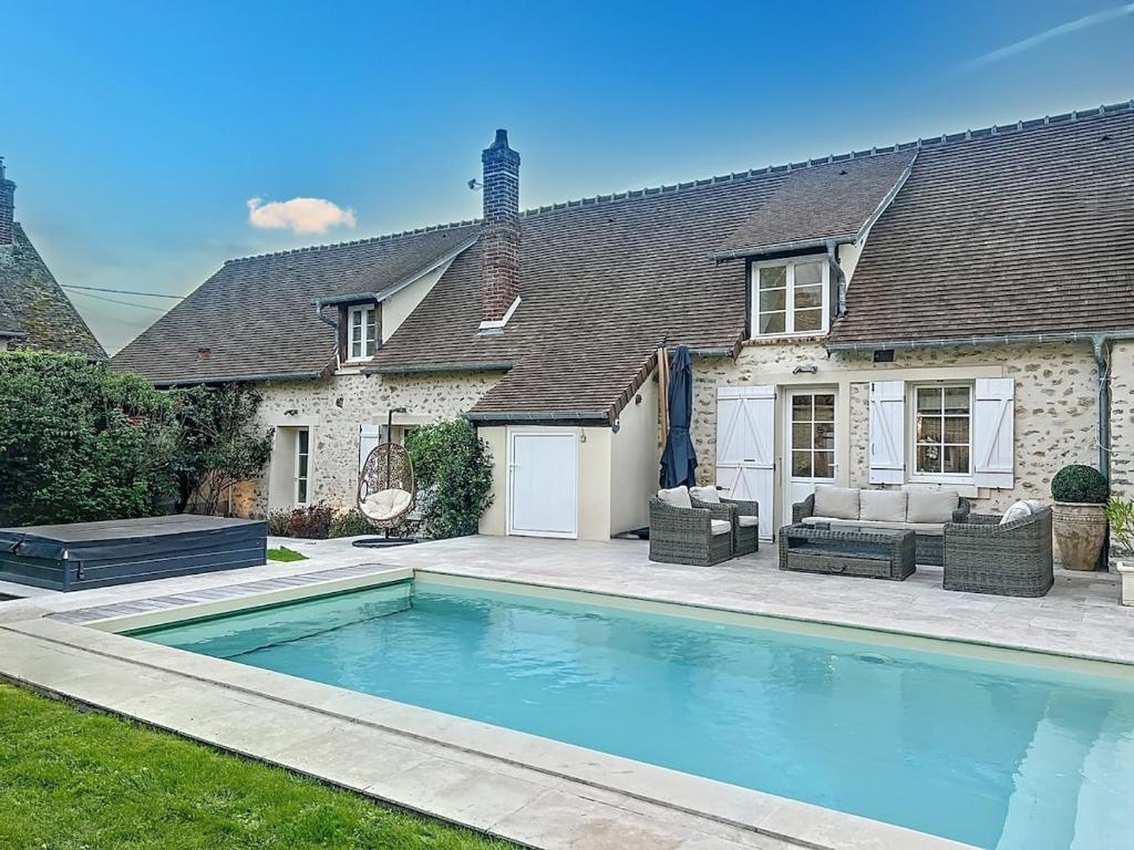 a house with a swimming pool in front of a house at Beautiful longere with pool in Courcelles-lès-Gisors