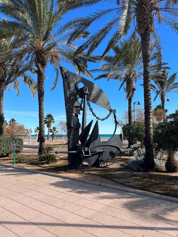 a large metal sculpture sitting between palm trees at Wohnung in Chilches in Xilxes