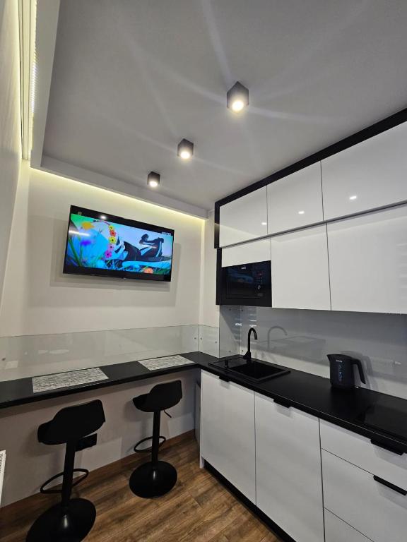 a kitchen with white cabinets and a tv on the wall at Vistula Center in Płock