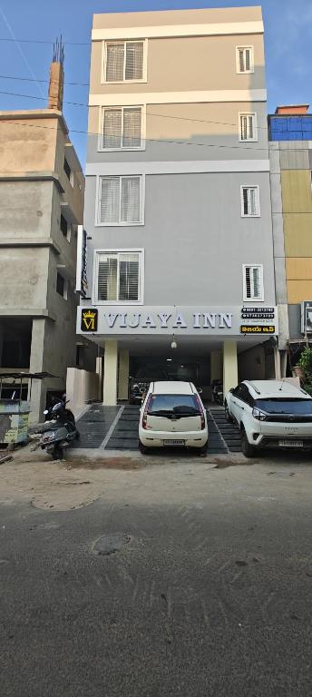 two cars parked in a parking lot in front of a building at Vijaya Inn in Visakhapatnam