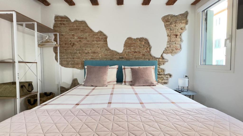 a bedroom with a bed with a brick wall at Maison Studio in Chioggia