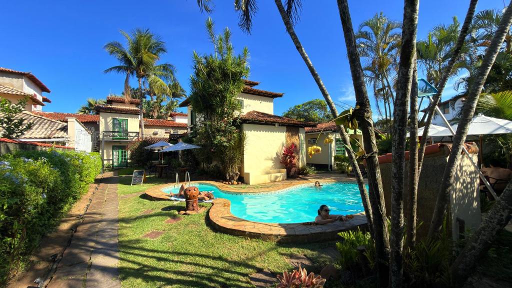 a swimming pool in a yard with two people in it at Pousada Sonho Verde in Rio das Ostras