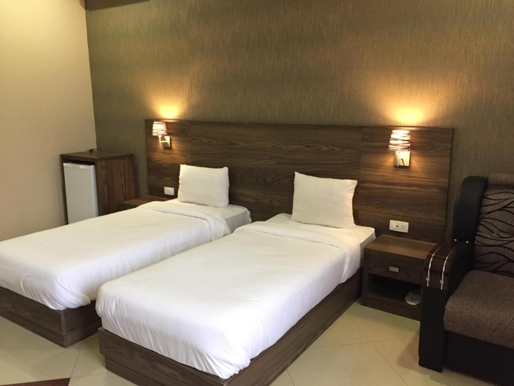 una habitación de hotel con 2 camas y una silla en Primer Hotel, en Ereván