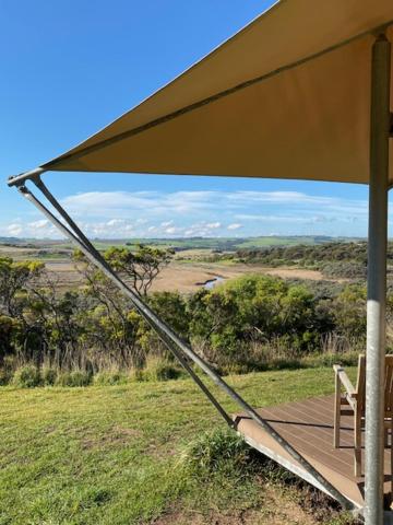 a chair under an umbrella on a wooden deck at Pebble Point in Princetown