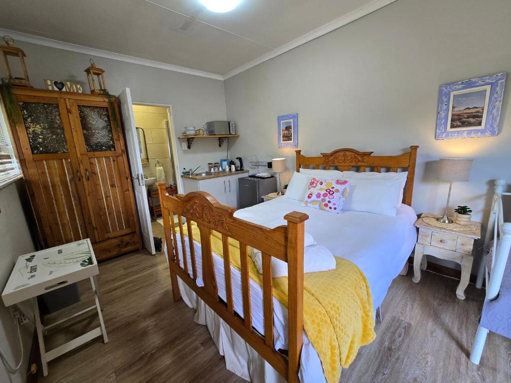 a bedroom with a large bed and a kitchen at Modern rustic private flat in Bloemfontein