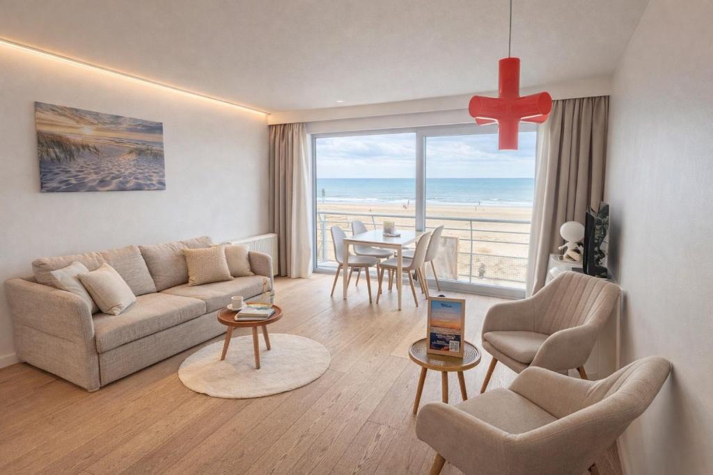 a living room with a couch and a table with chairs at Studio zwembad met frontaal zeezicht in Ostend