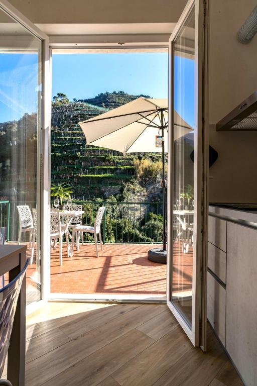 a kitchen with an open door to a deck with an umbrella at Macaia Family Apartment with AC in Vernazza