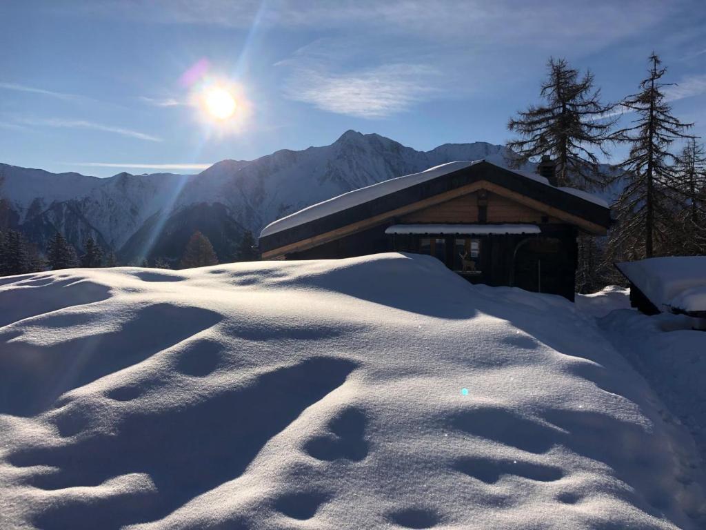 a snow covered building with the sun in the background at Untere Schweibe in Riederalp