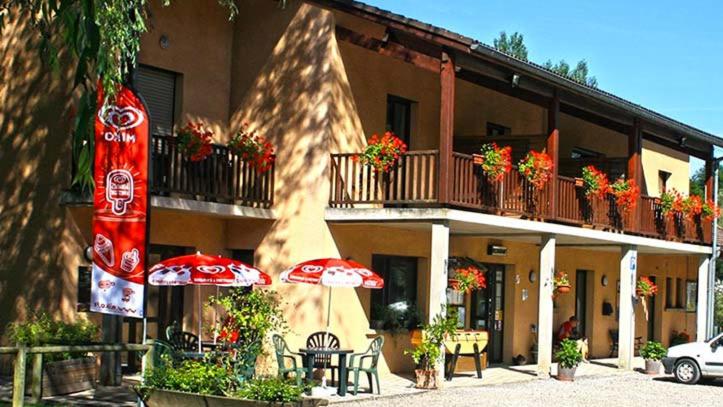 a building with tables and umbrellas in front of it at Chambres les 4 saisons in Oust