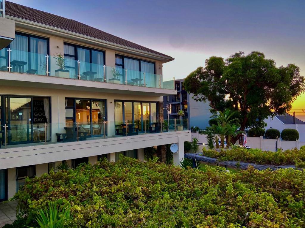 a building with balconies and tables and a tree at Grande Hotel in Cape Town