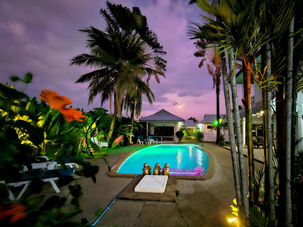 two people standing in front of a swimming pool at night at Sansuko Ville Panwa in Ban Bo Rae