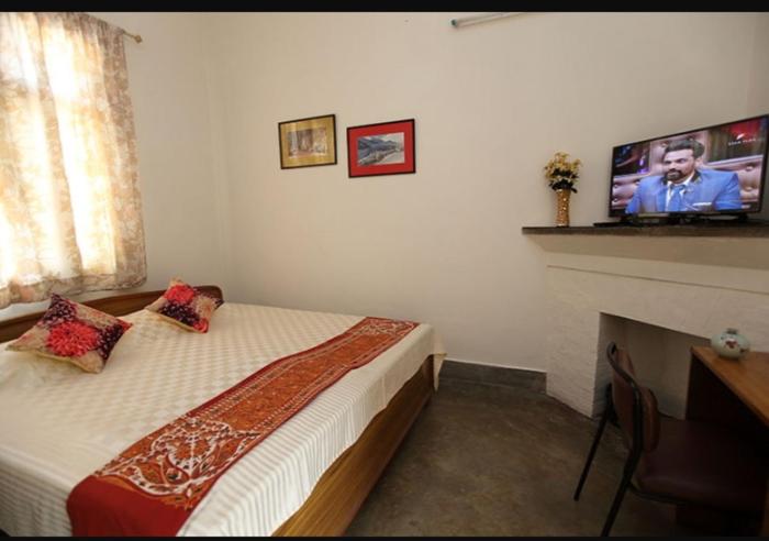 a bedroom with a bed with a fireplace and a tv at Chaudhary dharamshala in Jāmb