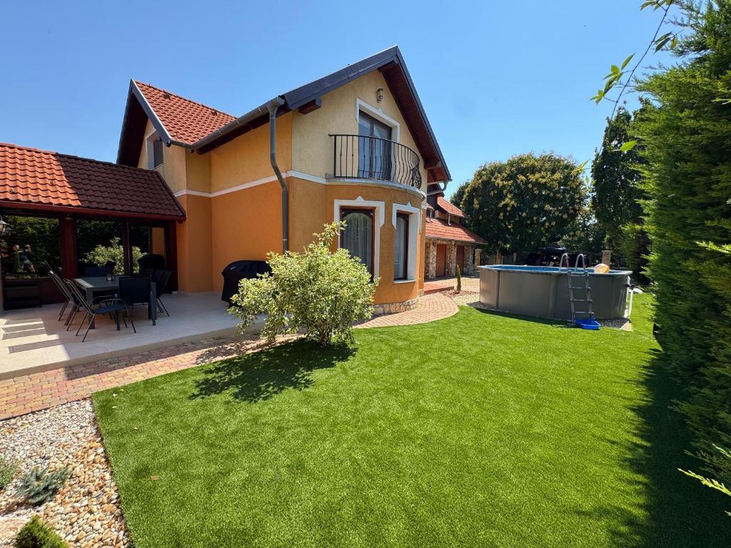 a house with a yard with green grass at Vianelli apartman in Zamárdi