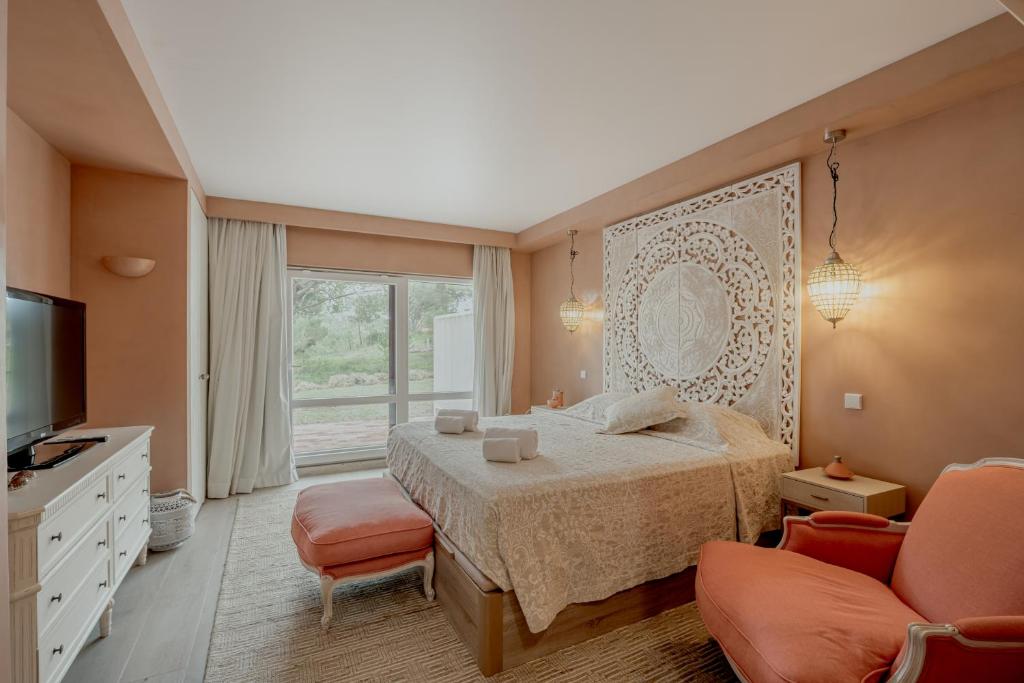 a bedroom with a bed and two chairs and a television at Quinta do Lago Duplex - Beach & Golf Algarve in Loulé