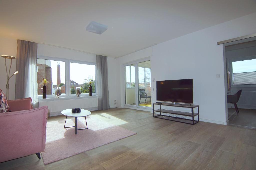 a living room with a tv and a couch and a table at Stadtlounge Norden in Norden