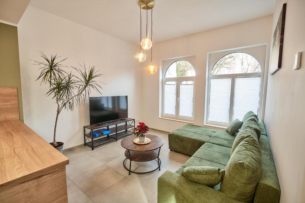 a living room with a green couch and a tv at Riverside Holiday in Eupen