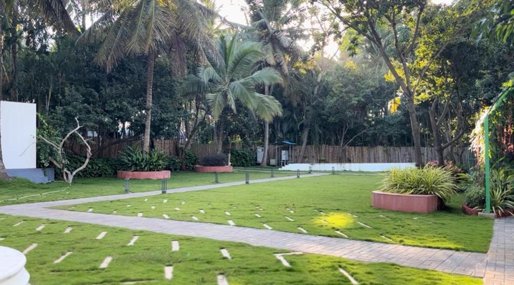 a park with a lawn with trees and a sidewalk at Mandala Resort in Sondekoppa