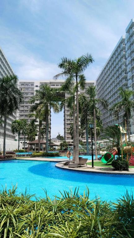 a swimming pool with palm trees in front of a building at Nygel Staycation at Shell Residences in Sampong