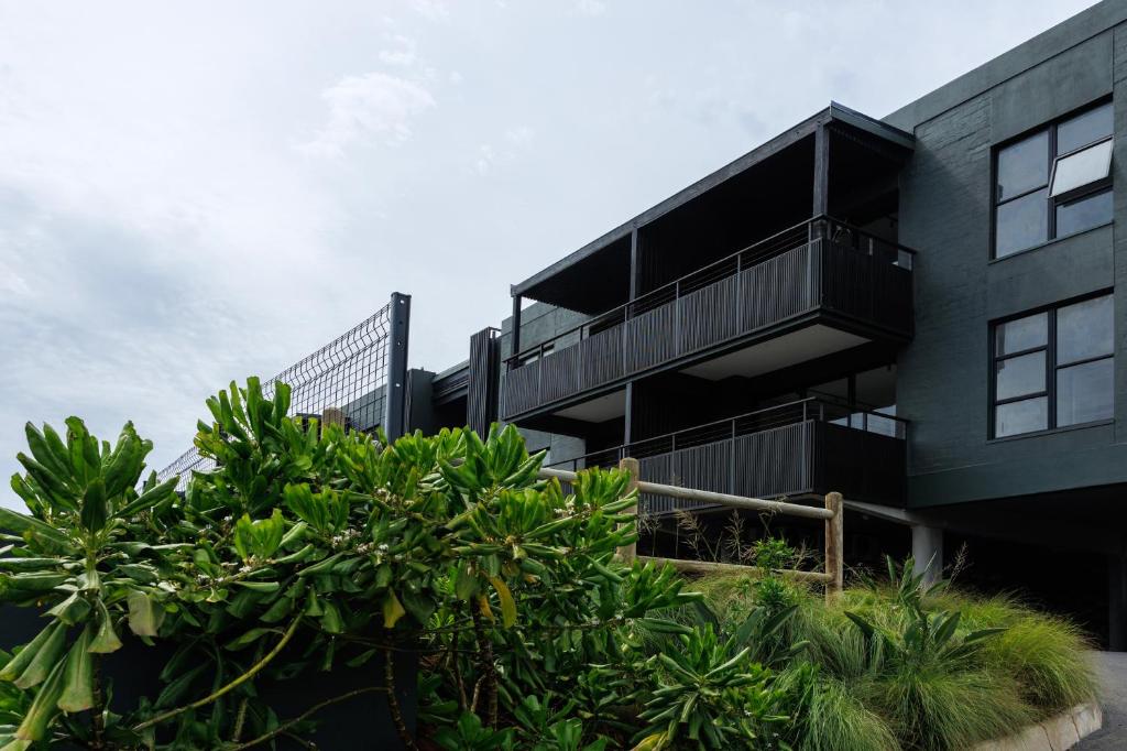 a black building with trees in front of it at Husk 17 - Sheffield Beach in Ballito