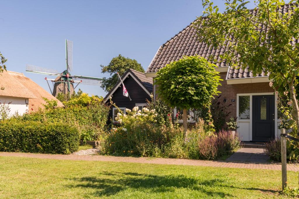 a house with a windmill in the background at Zalk blijven slapen in Zalk