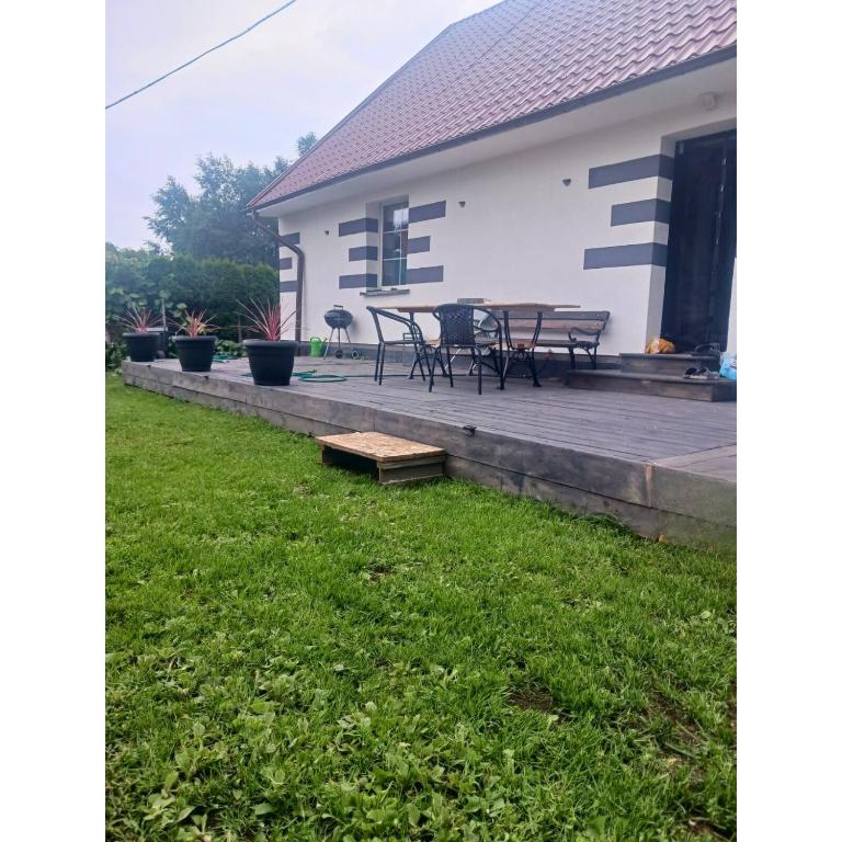 a backyard with a deck and a table and chairs at dom na gwarnej in Osłonin