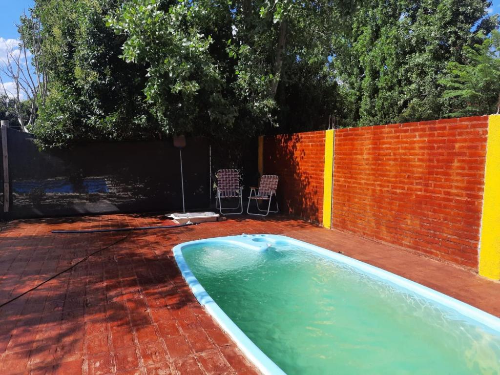 a swimming pool in a yard next to a brick fence at Cabaña Puntana in La Punta