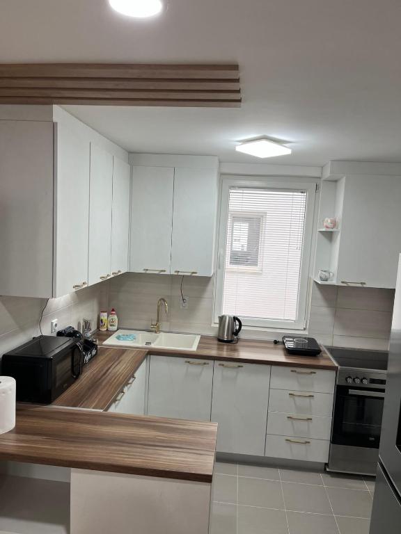 a kitchen with white cabinets and a sink and a window at Pantelej gates in Niš