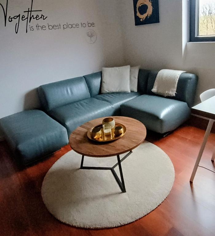 a living room with a blue couch and a coffee table at Au Coin du Bois in Theux