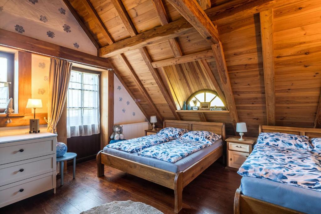 a bedroom with two beds and a wooden ceiling at Ranczo Pod Strzechą in Stara Kamienica