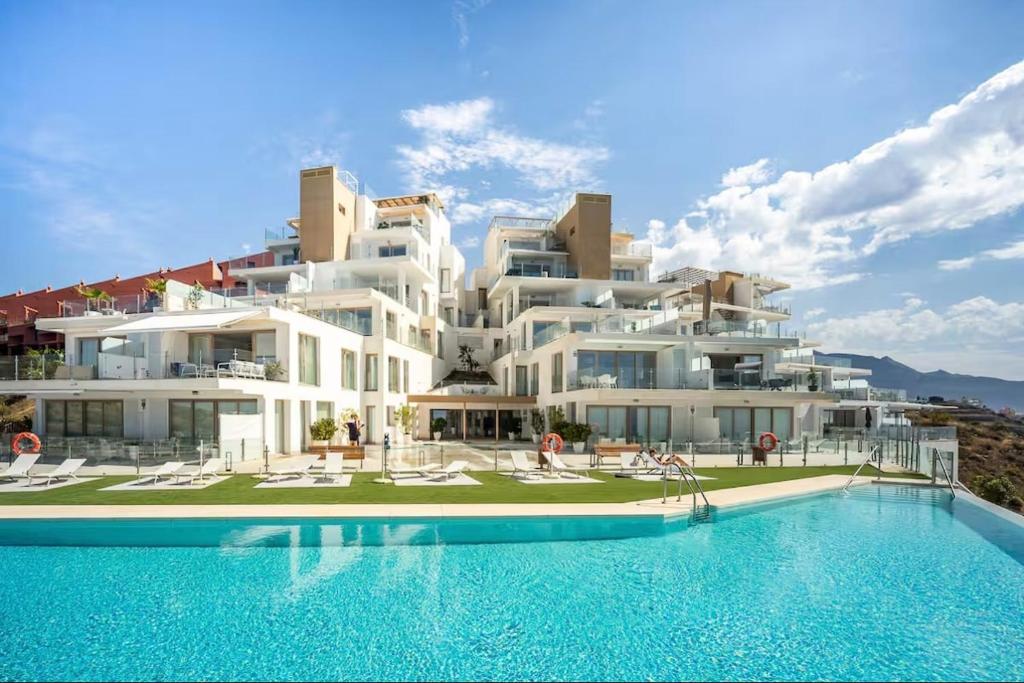 a large white building with a swimming pool in front of it at Seafront 2B Apartment with Pool, Spa & Gym Torrox in Torrox