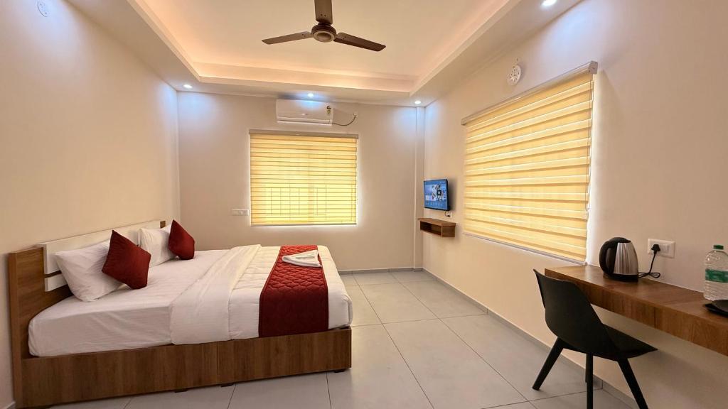 a bedroom with a bed and a desk and a window at Misty Suite Infopark in Cochin