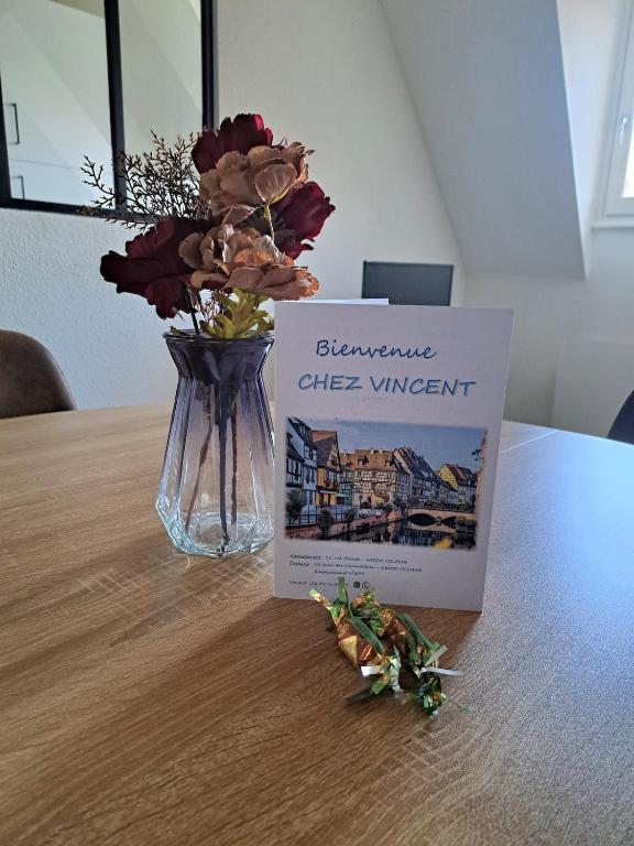 a book sitting on a table next to a vase with flowers at Chez Vincent - Centre Historique de Colmar avec parking inclus in Colmar